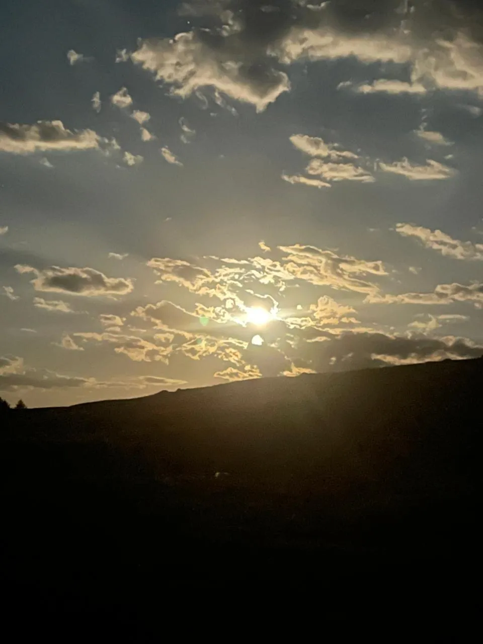 Last light over a Mongolian ridge, clouds opening above a darkened horizon.